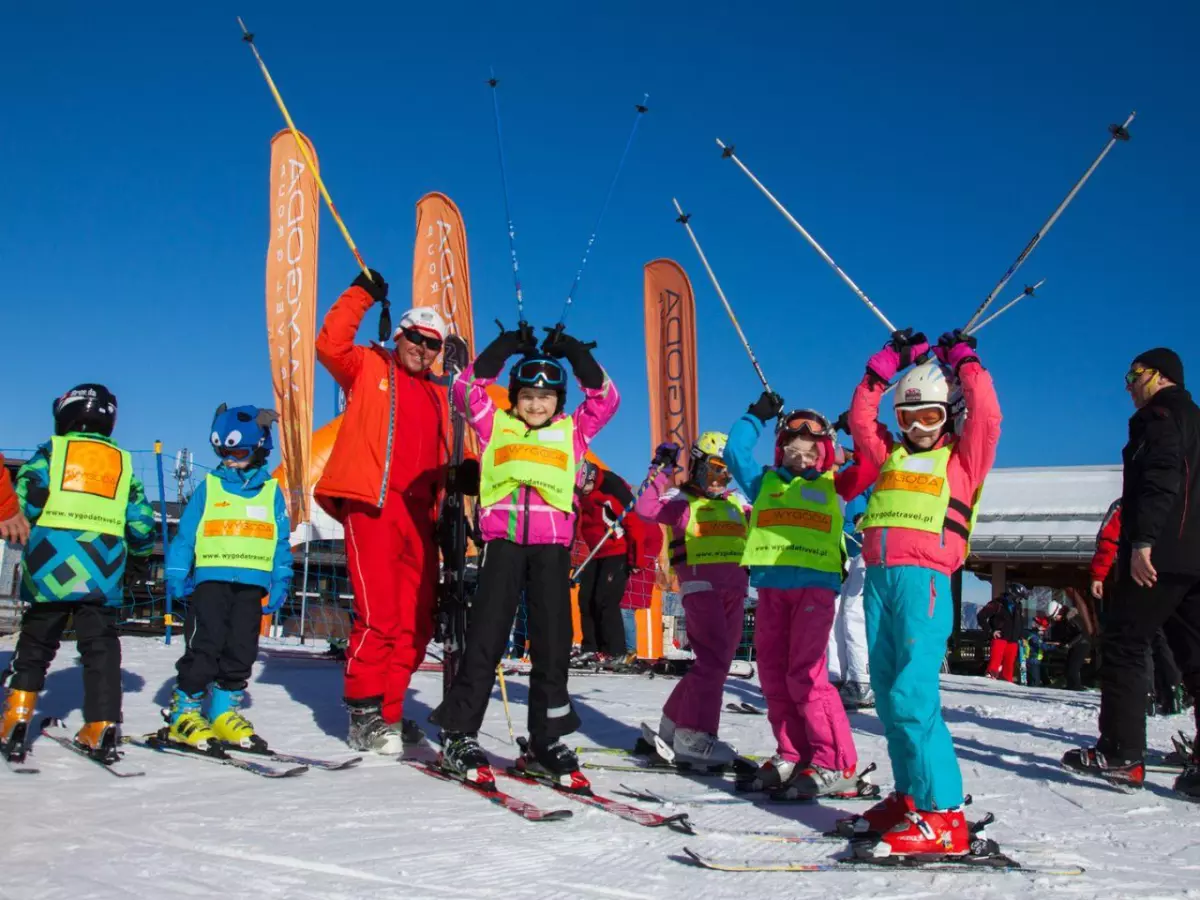 Zadowolona grupa dzieci z instruktorem na nartach.