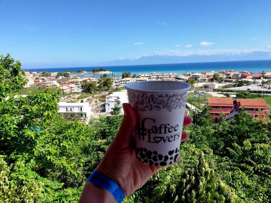 widok kubka z kawą na tle domków plazy i morza.